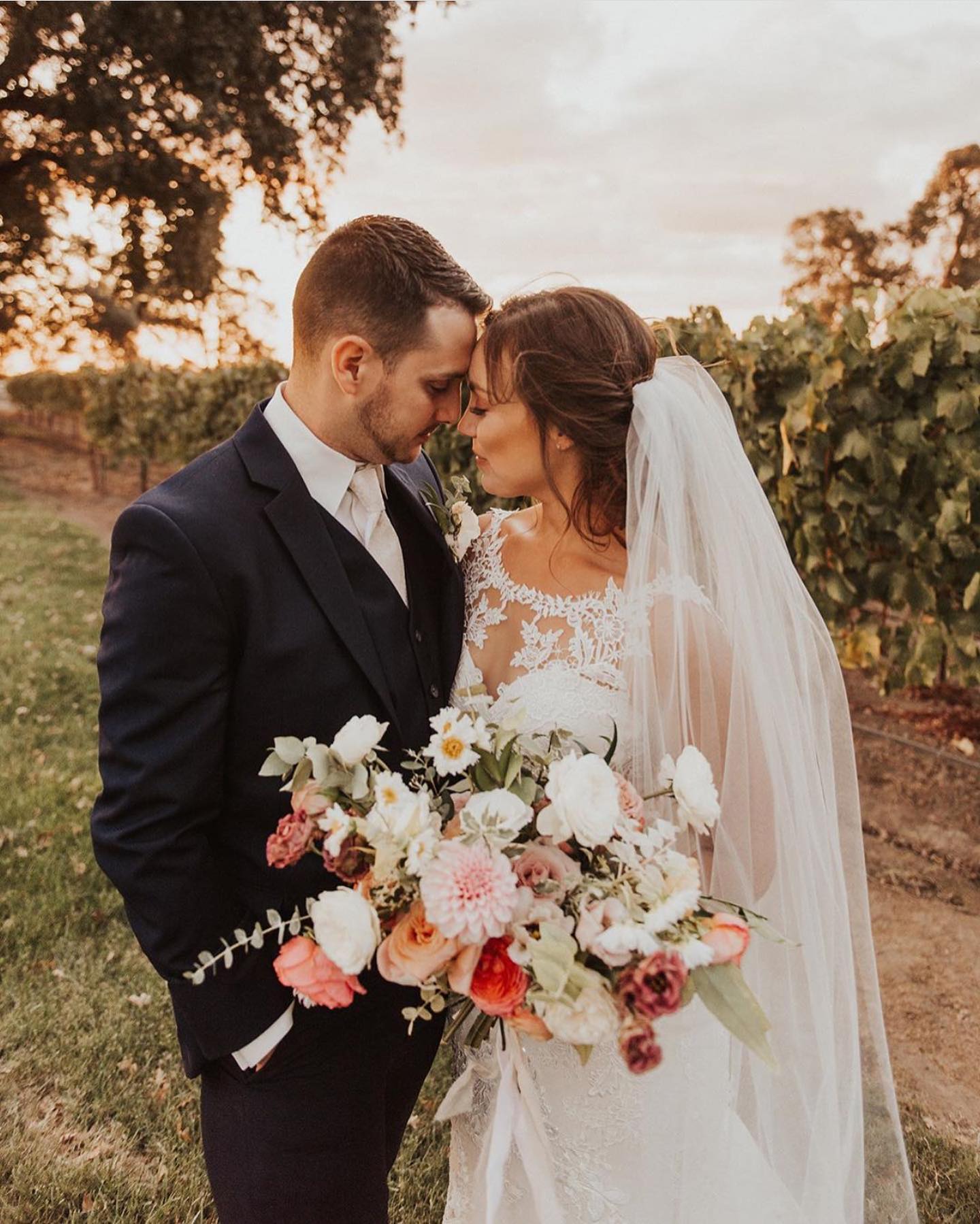 Groom is kissing brunette bride in white wedding dress