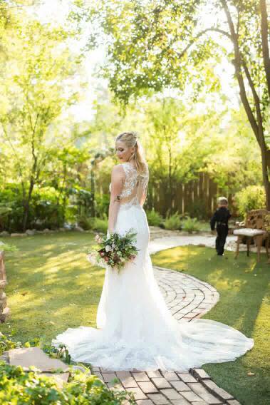 Blonde bride is holding flowers at courtyard. Blackface photo