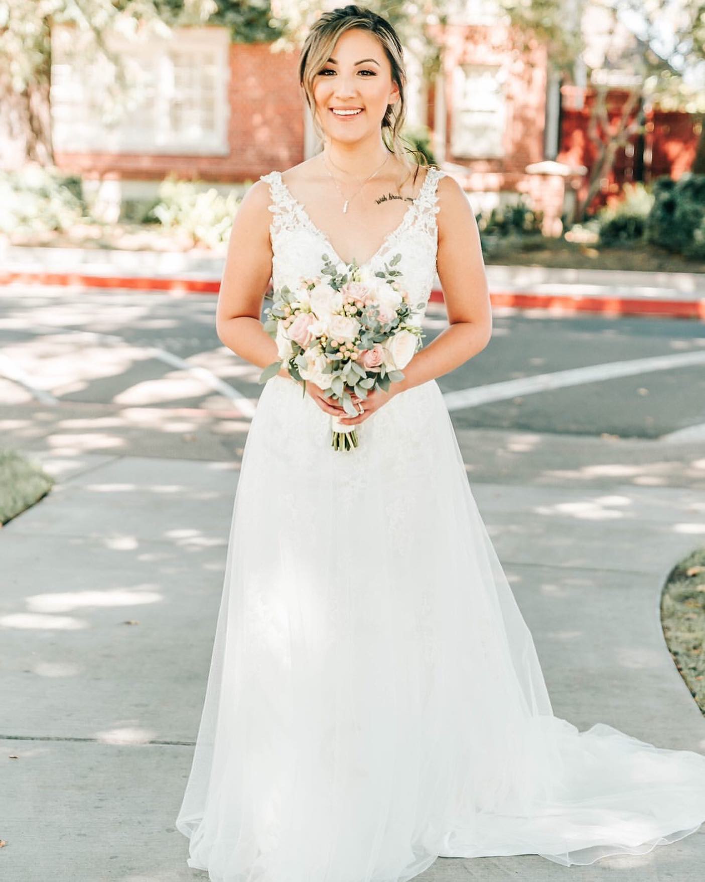 Blonde Bride in white wedding dress with flowers at street